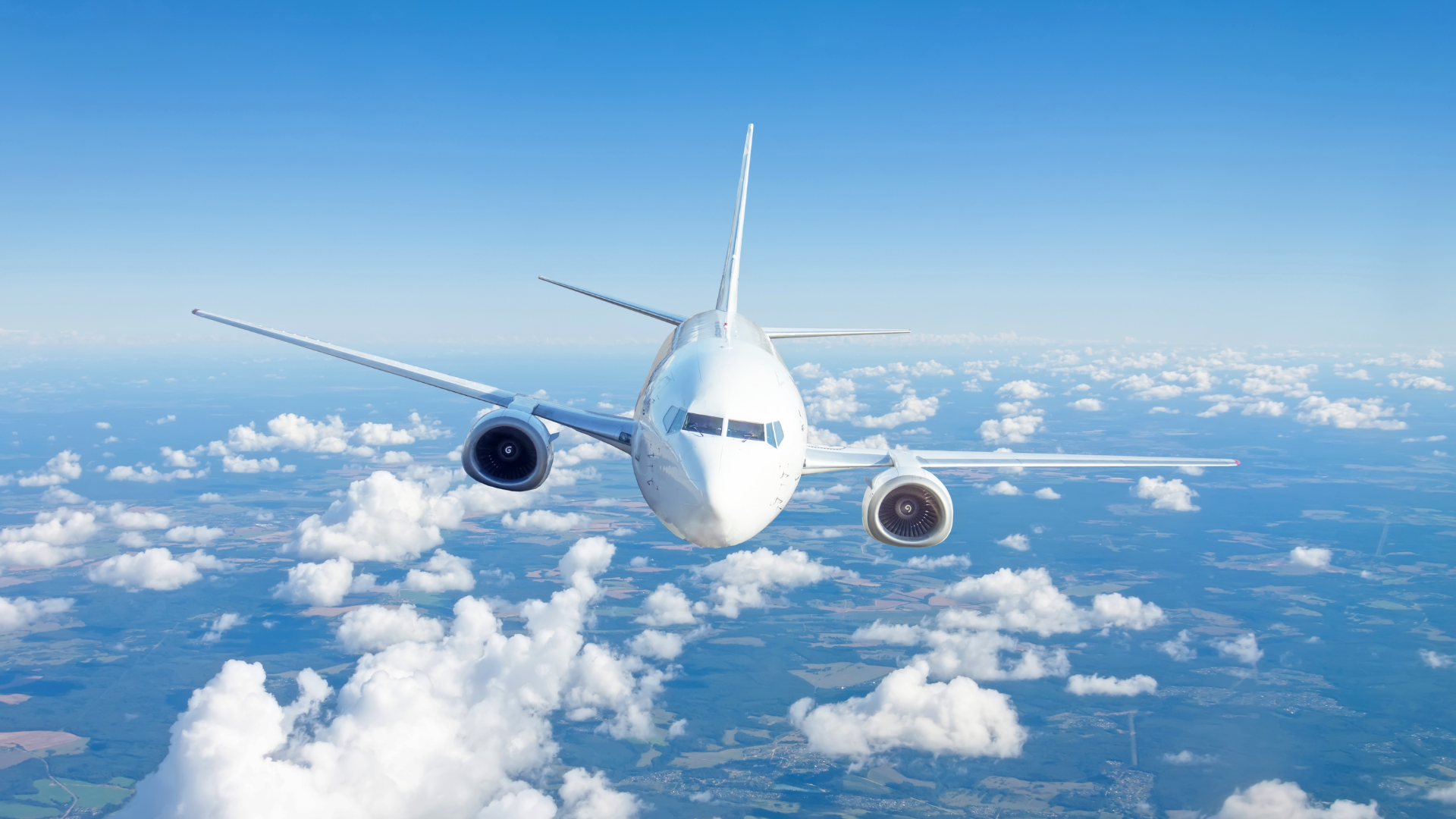 Commercial aircraft flying above clouds